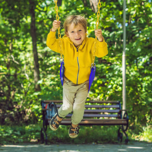 Young boy swinging in a yard. 